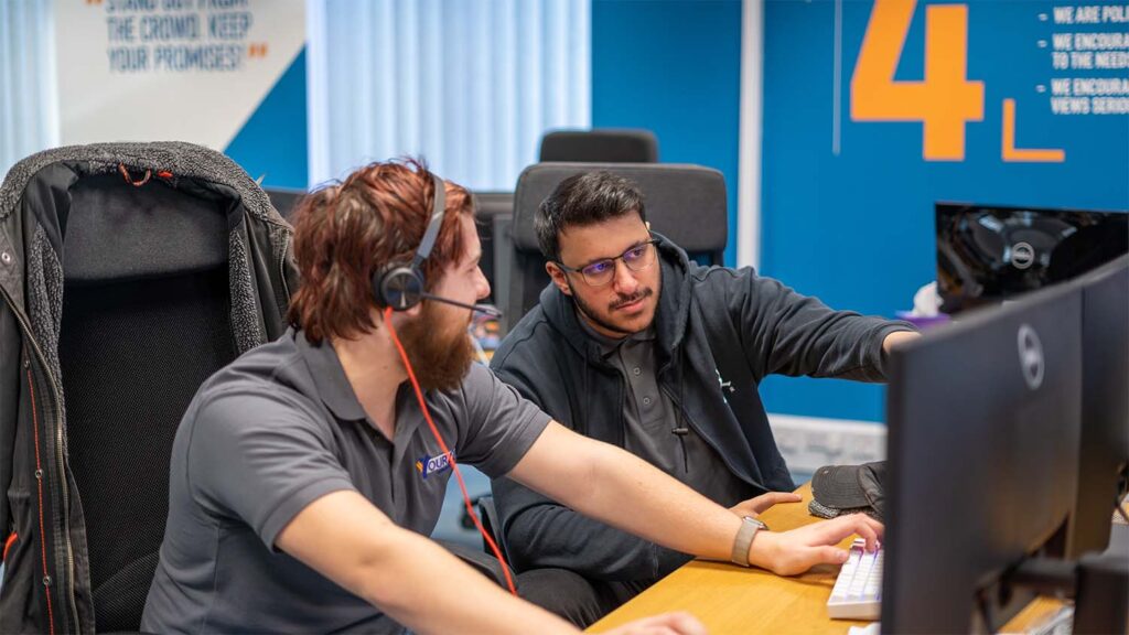 Your IT Department member advising colleague in front of computer