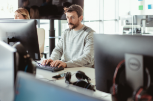 Casually-dressed office worker staring intently at computer screen