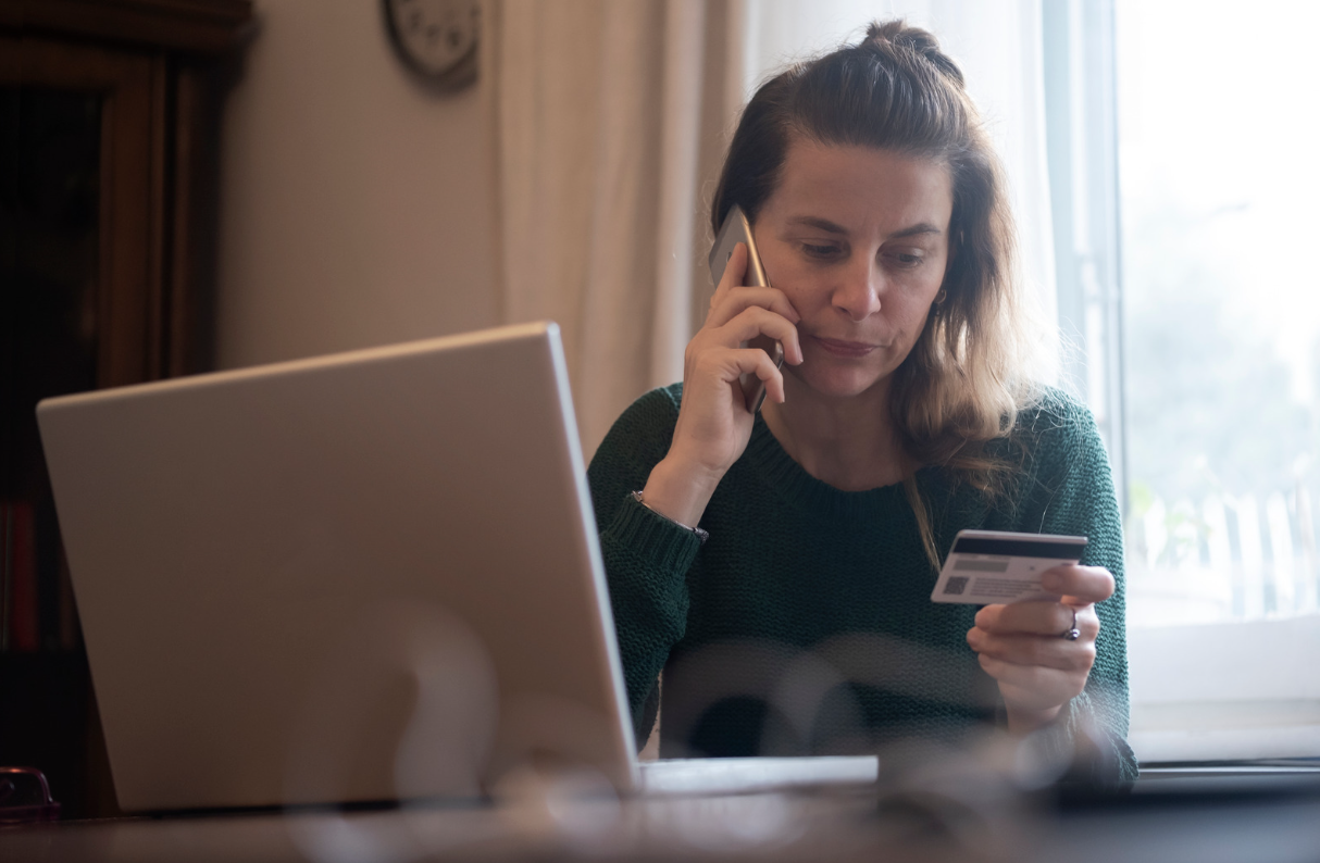 Concerned woman holding credit card and ringing bank over internet scam