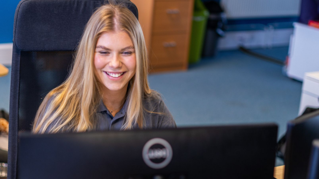 Smiling Your IT Department staff member in front of computer screen